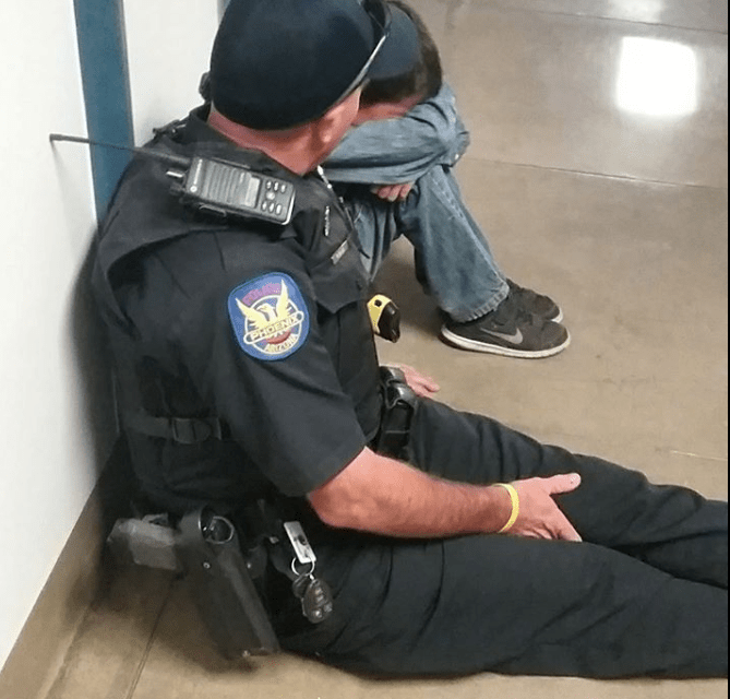 Police Officer Sits On Floor, Comforts Crying Student